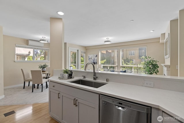 kitchen with a wealth of natural light, dishwasher, light countertops, and a sink