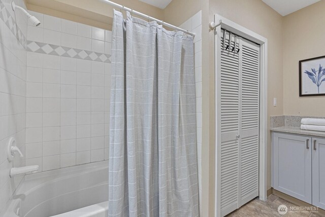 full bathroom with a closet, vanity, and shower / bathtub combination with curtain