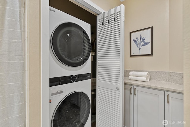 washroom with stacked washer and dryer and laundry area