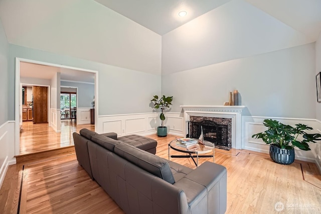 living area with vaulted ceiling, wainscoting, a fireplace, and wood finished floors