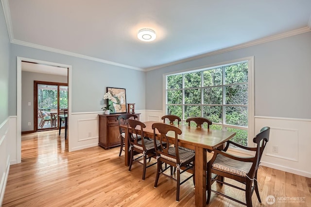 dining space featuring wainscoting, light wood-style flooring, and ornamental molding