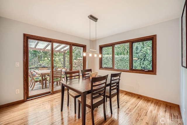 dining space with light wood-style flooring and baseboards