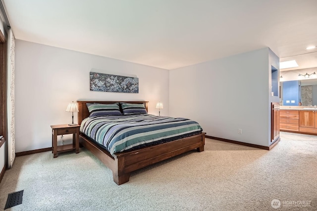 bedroom featuring light carpet, visible vents, ensuite bath, and baseboards