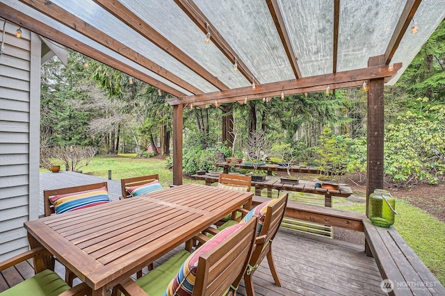 wooden terrace with a lawn and outdoor dining area