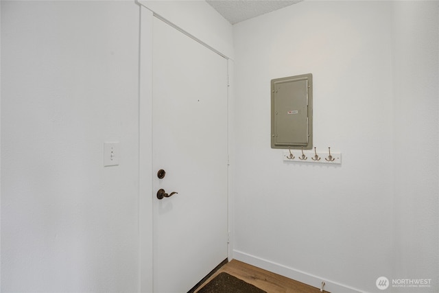 doorway featuring electric panel, baseboards, and wood finished floors