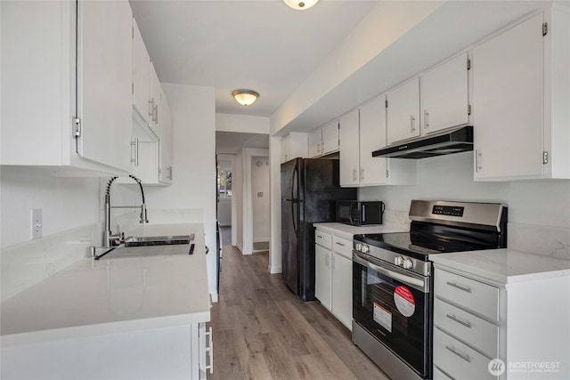 kitchen featuring electric range, a sink, light wood-style floors, under cabinet range hood, and white cabinetry