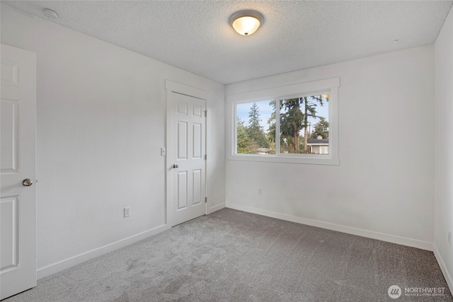 empty room with baseboards, carpet floors, and a textured ceiling