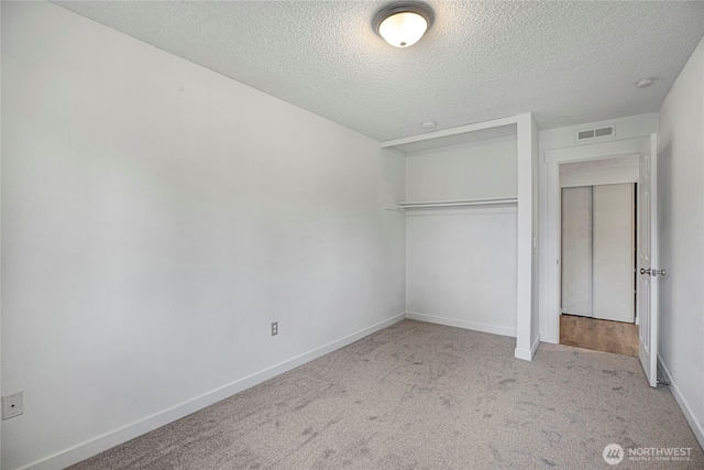 unfurnished bedroom featuring visible vents, baseboards, carpet floors, a closet, and a textured ceiling