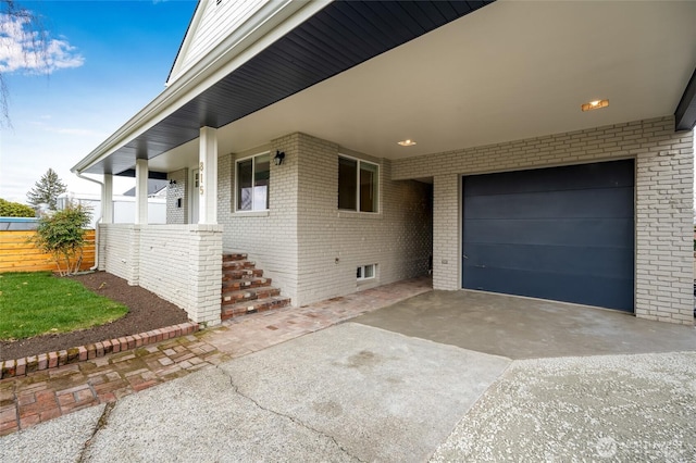 view of home's exterior featuring brick siding, driveway, and fence