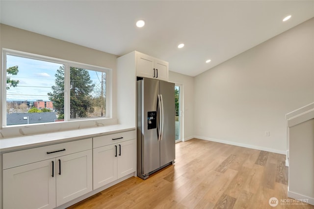 kitchen with light wood-type flooring, white cabinetry, recessed lighting, stainless steel fridge, and baseboards