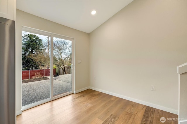 empty room featuring vaulted ceiling, recessed lighting, light wood-style floors, and baseboards