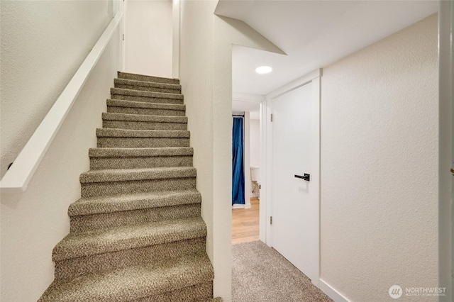 staircase featuring recessed lighting, carpet, and a textured wall