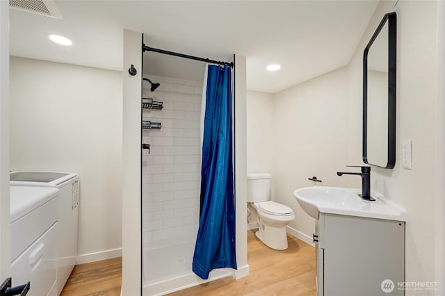 bathroom with washer and dryer, visible vents, toilet, and wood finished floors