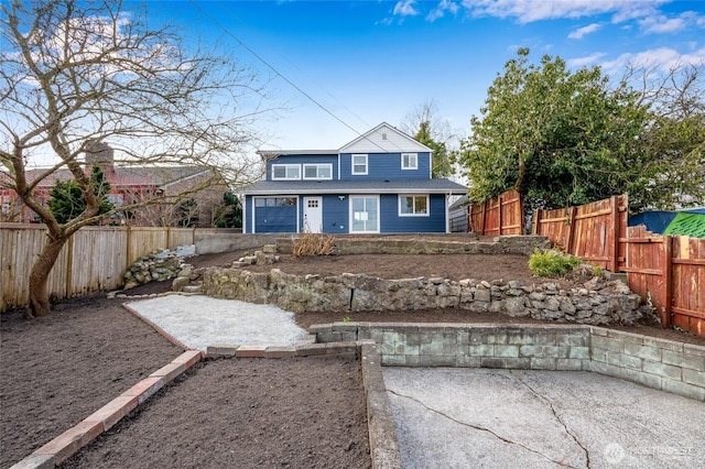 view of front of home featuring a patio area, a fenced backyard, and a garage