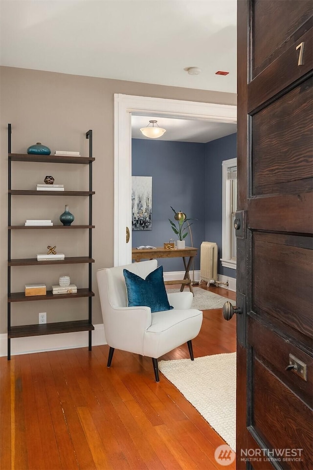 living area featuring radiator, baseboards, and hardwood / wood-style floors