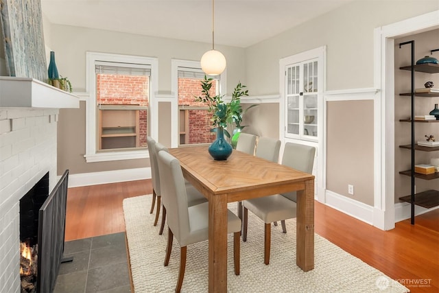 dining space featuring dark wood finished floors, a fireplace, and baseboards