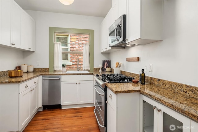 kitchen featuring white cabinetry, stainless steel appliances, light wood-type flooring, and a sink