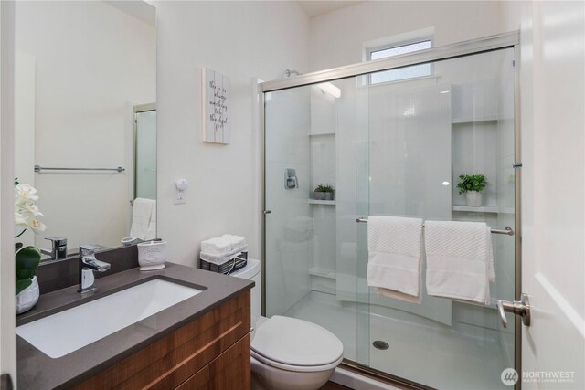 bathroom featuring a stall shower, toilet, and vanity