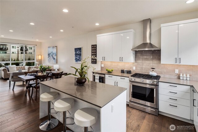 kitchen with stainless steel gas range oven, backsplash, dark wood finished floors, recessed lighting, and wall chimney exhaust hood