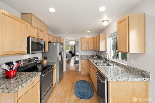 kitchen featuring a sink, stainless steel appliances, light brown cabinetry, and light wood finished floors