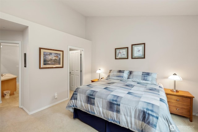 bedroom with light colored carpet, ensuite bath, lofted ceiling, and baseboards