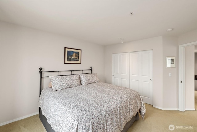 bedroom with light colored carpet, a closet, and baseboards