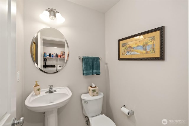 bathroom featuring washer / dryer, toilet, and a sink