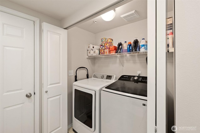 washroom featuring laundry area, separate washer and dryer, and visible vents