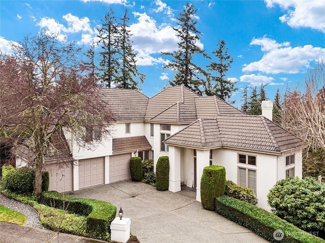 view of front facade with stucco siding, a chimney, driveway, and a tiled roof