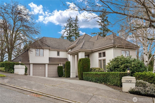 view of front of home with a tiled roof, stucco siding, driveway, and an attached garage