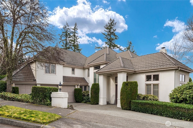 view of front of home with a tile roof, stucco siding, driveway, and a chimney