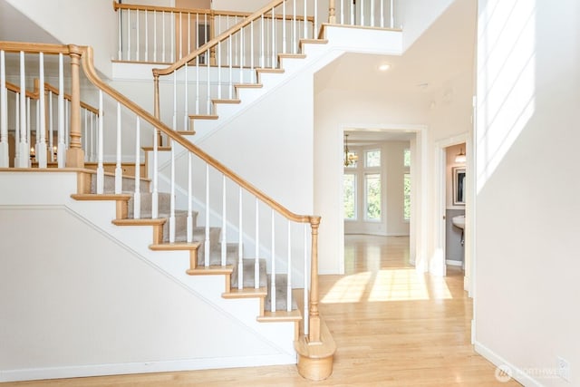 stairway with a high ceiling, wood finished floors, and baseboards