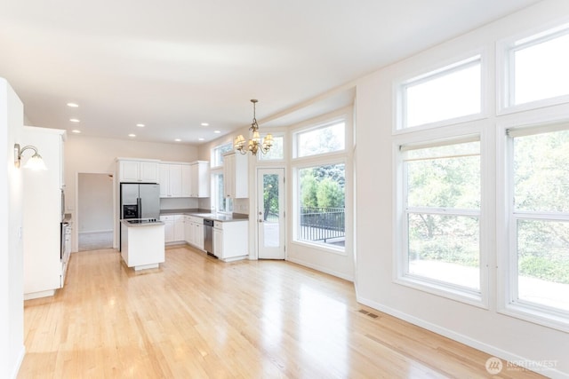 kitchen with visible vents, stainless steel appliances, white cabinetry, a notable chandelier, and light wood-type flooring