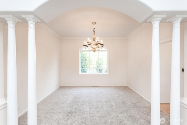 carpeted spare room featuring an inviting chandelier, decorative columns, crown molding, and baseboards