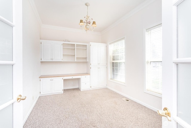 unfurnished office featuring crown molding, baseboards, light carpet, an inviting chandelier, and built in study area