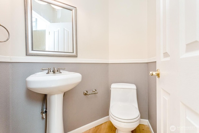 bathroom with toilet, wood finished floors, and baseboards