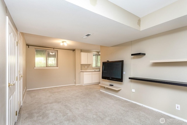 unfurnished living room with visible vents, light colored carpet, plenty of natural light, and baseboards