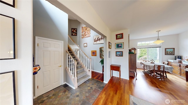 entrance foyer featuring baseboards, wood finished floors, and stairs