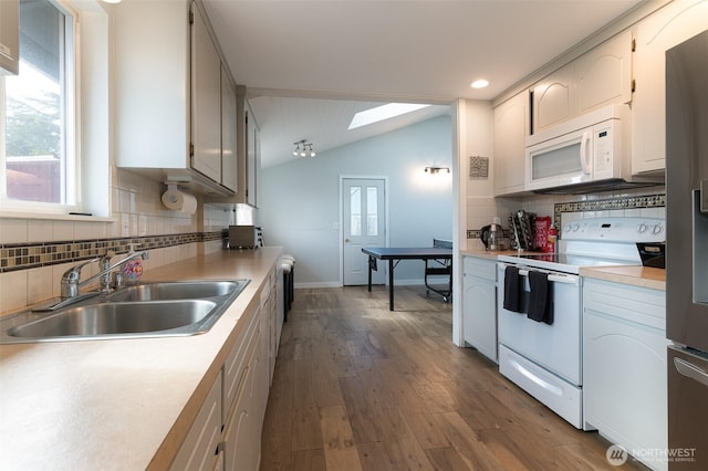 kitchen featuring dark wood-type flooring, light countertops, vaulted ceiling, white appliances, and a sink