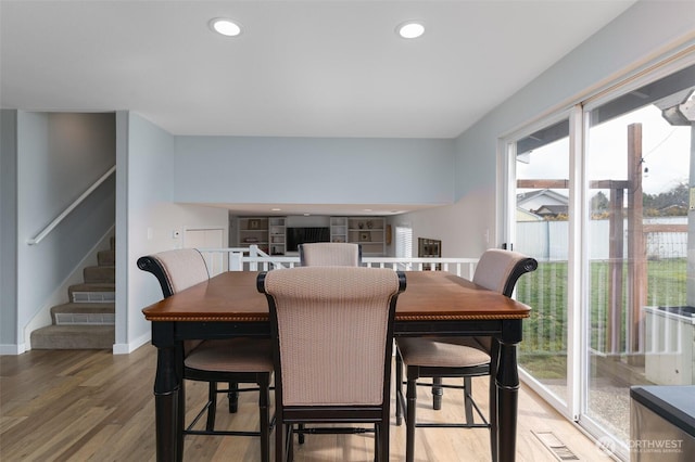 dining room with recessed lighting, baseboards, light wood-style floors, and stairs