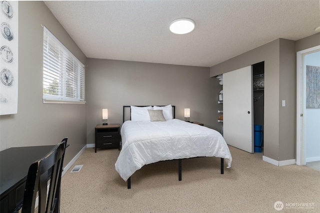 bedroom with visible vents, a textured ceiling, a closet, baseboards, and light colored carpet