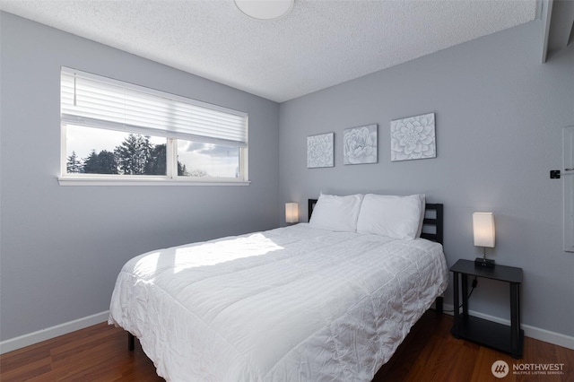 bedroom with wood finished floors, baseboards, and a textured ceiling