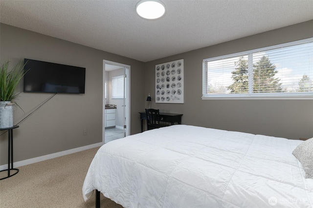 bedroom featuring a textured ceiling, ensuite bathroom, and baseboards