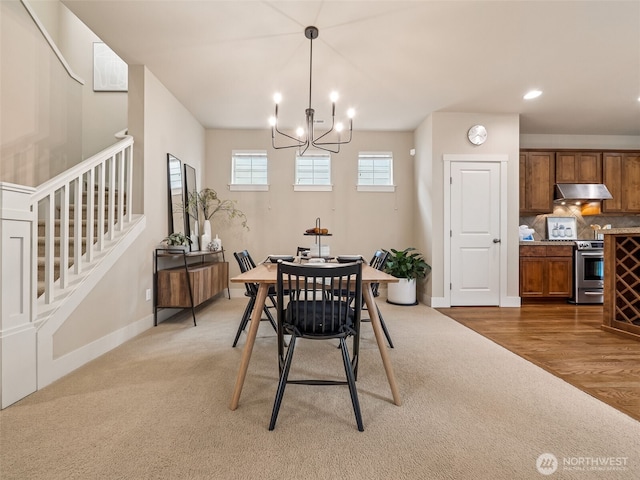 dining space featuring light carpet, a notable chandelier, recessed lighting, baseboards, and stairs