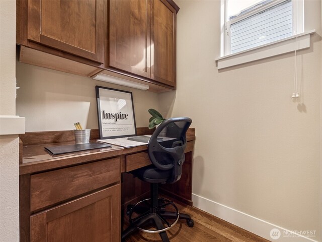 office space with built in study area, baseboards, and wood finished floors