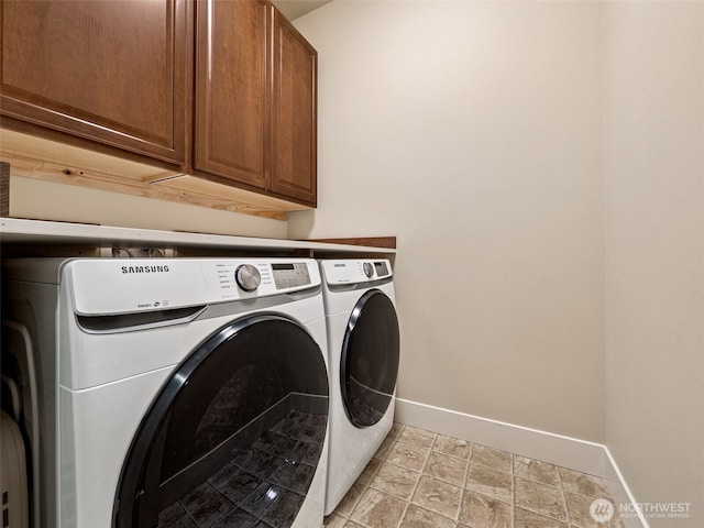 laundry room with cabinet space, washer and dryer, and baseboards