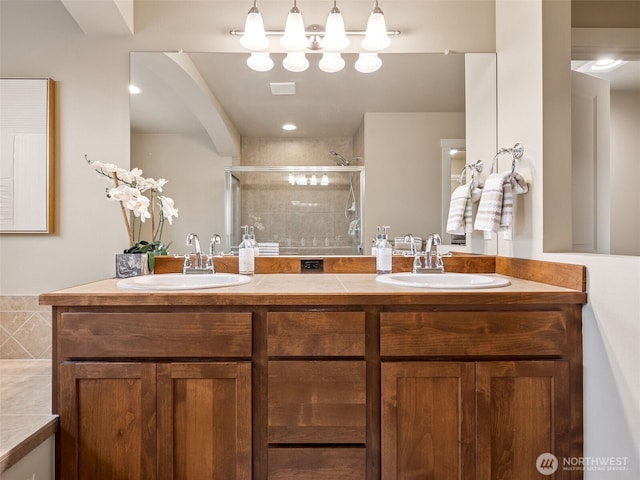 full bath with a shower stall, double vanity, and a sink