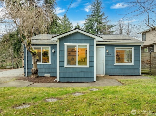 back of house featuring a shingled roof and a yard