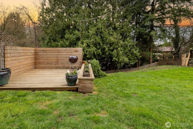 yard at dusk featuring a deck and fence