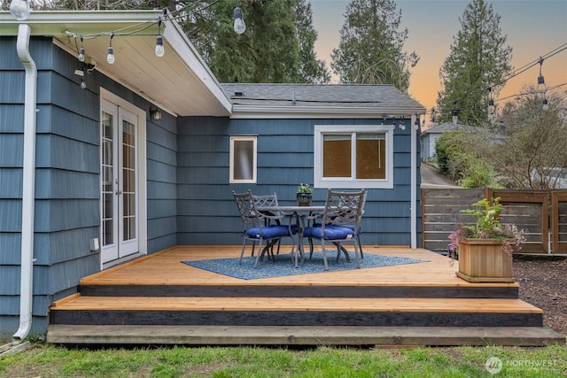 wooden terrace featuring french doors, outdoor dining space, and fence